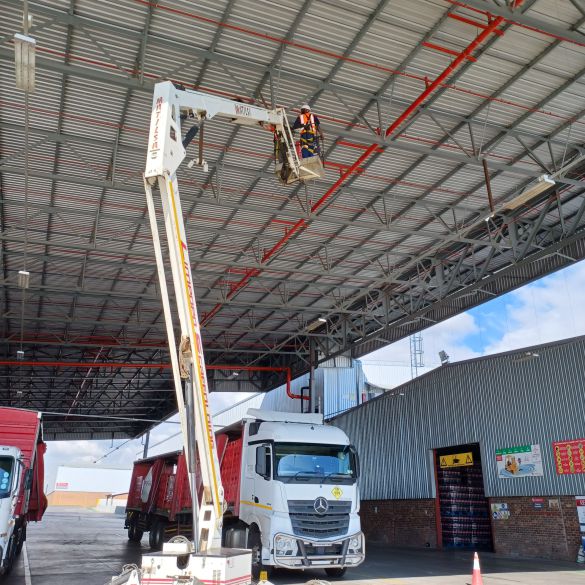 Specifusion installation team executing safe, high-altitude signage installation using a cherry picker at the CCBSA facility in Polokwane, Limpopo